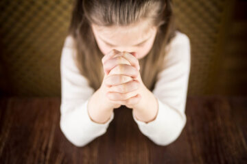 The girl prays at a table